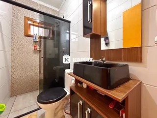 Banheiro com box de vidro e bancada de madeira.