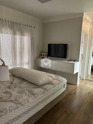 Quarto com janela e piso de madeira clara.