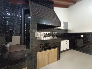 Detalhe da área de cozinha com revestimento de cerâmica escura e fogão em aço inoxidável.