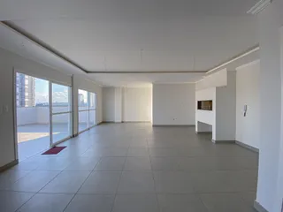 Sala ampla com piso de cerâmica e portas de vidro voltadas para o exterior.
