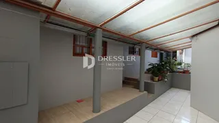 Corredor com vigas de madeira expostas e coluna de concreto.