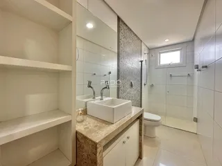 Banheiro moderno com bancada de mármore e box de vidro.