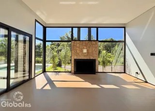 Sala de estar com grandes janelas de vidro e lareira de pedra.