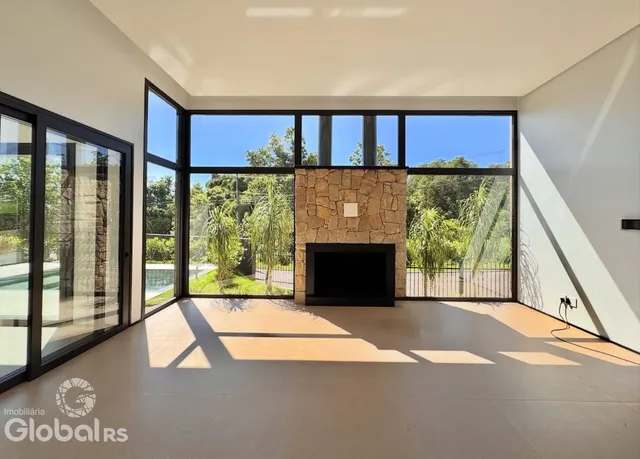 Sala de estar com grandes janelas de vidro e lareira de pedra.