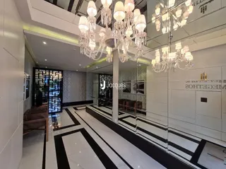 Corredor interno de um imóvel com piso em preto e branco e iluminação moderna.