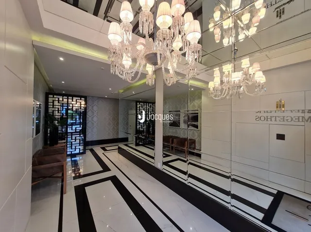 Corredor interno de um imóvel com piso em preto e branco e iluminação moderna.
