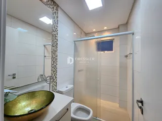 Banheiro com box de vidro e pia de ouro.