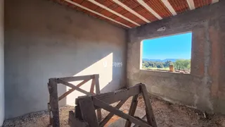 Interior de uma sala em construção com paredes de concreto aparente e janela para o exterior.