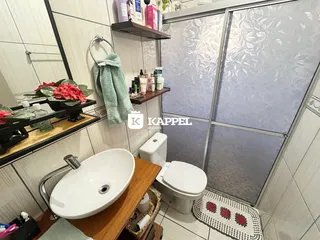 Banheiro com pia de apoio, vaso sanitário e box de vidro com vidro fosco.
