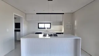 Vista da cozinha moderna com ilha branca e armários em Lajeado.