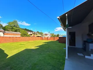 Vista da fachada de uma casa com um grande jardim gramado.