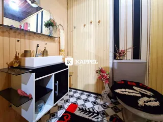 Foto de um banheiro com bancada preta e piso de azulejos geométricos.