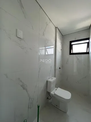 Banheiro com revestimento de azulejos brancos e piso claro.