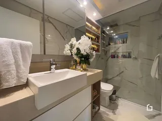 Banheiro moderno com bancada branca e revestimento em mármore.