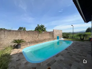 Vista de uma piscina externa em um pátio com muro de alvenaria.