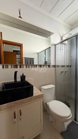Foto do interior de um banheiro com bancada e box de vidro.