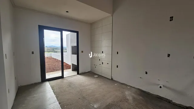 Interior de um espaço aberto com porta de vidro voltada para a paisagem externa.