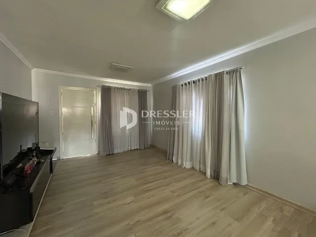 Ambiente interno de uma sala com piso de madeira clara.
