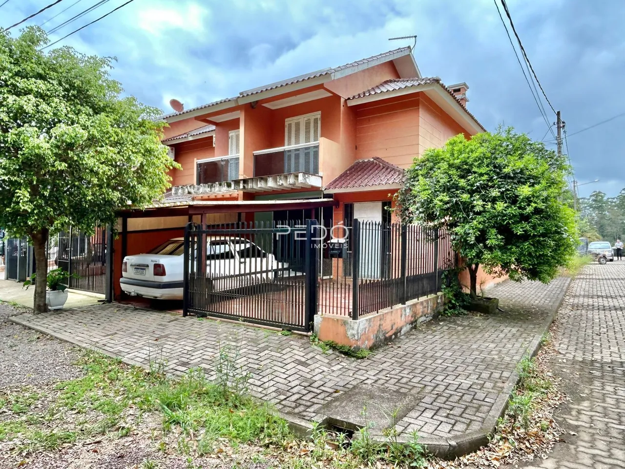 Fachada de uma casa em Lajeado, Brasil, com cerca e vegetação ao redor.
