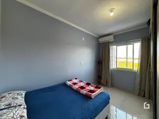 Quarto com cama azul e janela em um imóvel no Brasil.