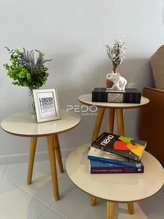 Uma mesa redonda de madeira decorada com plantas e livros está em um ambiente interno.