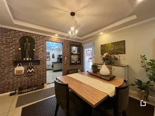 Interior de uma sala de jantar com parede de tijolos aparentes.