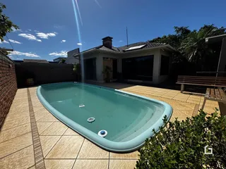 Vista externa de uma piscina e área de lazer em uma residência.