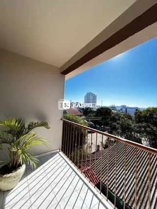 Vista da varanda com paisagem urbana e vegetação ao fundo.