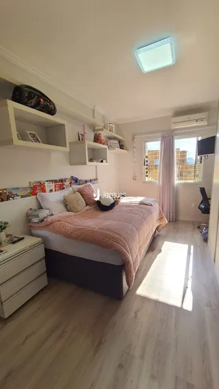 Quarto com cama e estantes brancas em um imóvel.