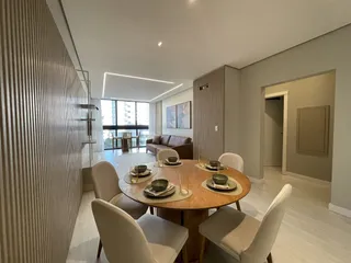 Sala de jantar moderna com mesa de madeira e cadeiras em um ambiente claro.