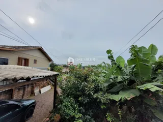 Vista externa de uma propriedade com vegetação densa no primeiro plano.