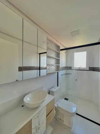 Banheiro moderno com revestimento em mármore e box de vidro.