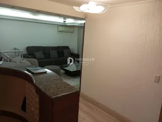 Vista interna de uma sala de estar com sofá e janela em um imóvel no Brasil.