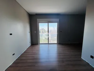 Vista interna de um ambiente com piso de madeira e porta de vidro.