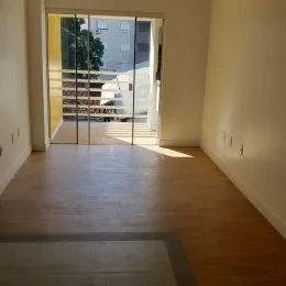 Hall de entrada com piso de madeira e porta de vidro.