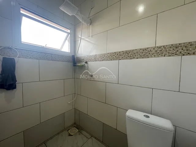 Foto interna de um banheiro com revestimento de azulejos claros.