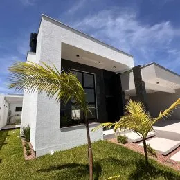 Fachada externa de uma casa moderna em Lajeado com gramado e palmeiras.