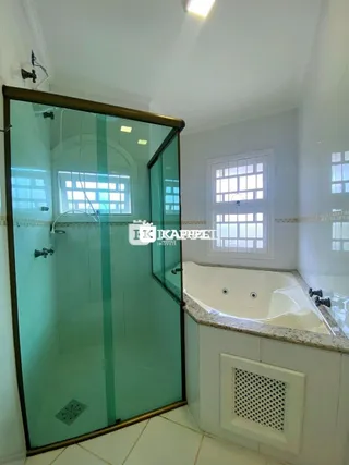 Banheiro com box de vidro e banheira em um ambiente claro.