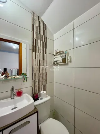 A foto mostra o interior de um banheiro com azulejos brancos.