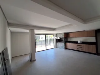 Ambiente interno de uma sala ampla com cozinha integrada e acesso a uma área externa.