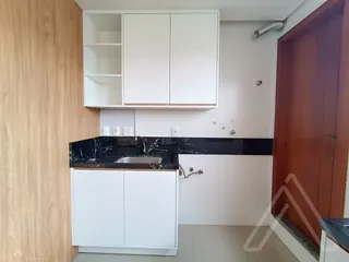 Cozinha moderna com armários brancos e bancada preta.