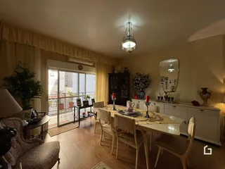 Ambiente interno de uma sala de jantar com piso de madeira e vista para o exterior.