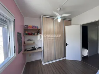 Quarto com parede rosa e armário de madeira na sala.