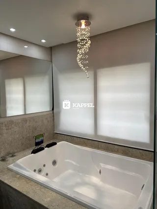 Foto de um banheiro com banheira branca e iluminação de lustre decorativo.