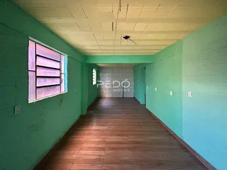 Corredor interno de uma residência com paredes verde-água e piso de madeira.