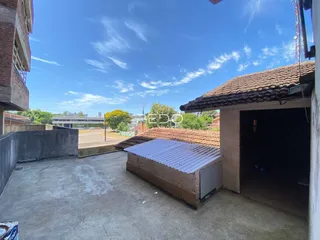 Vista de uma área externa com piso de concreto e telhado de telhas.