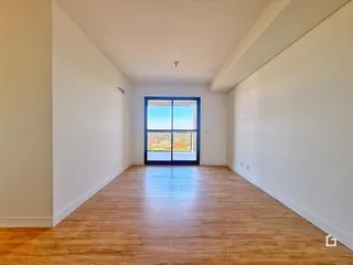 Sala de estar com piso de madeira e grande janela.