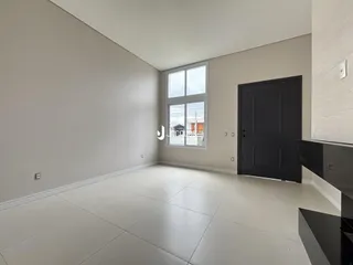 Uma sala de estar com paredes claras e piso de cerâmica.