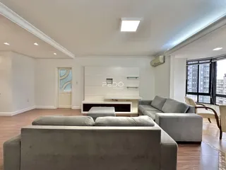 Sala de estar moderna com piso de madeira e sofá cinza.