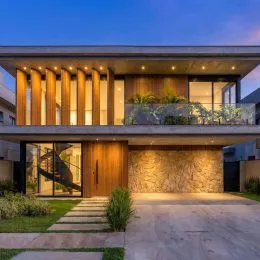 Fachada moderna de uma residência com revestimento de madeira e grandes portas de vidro.